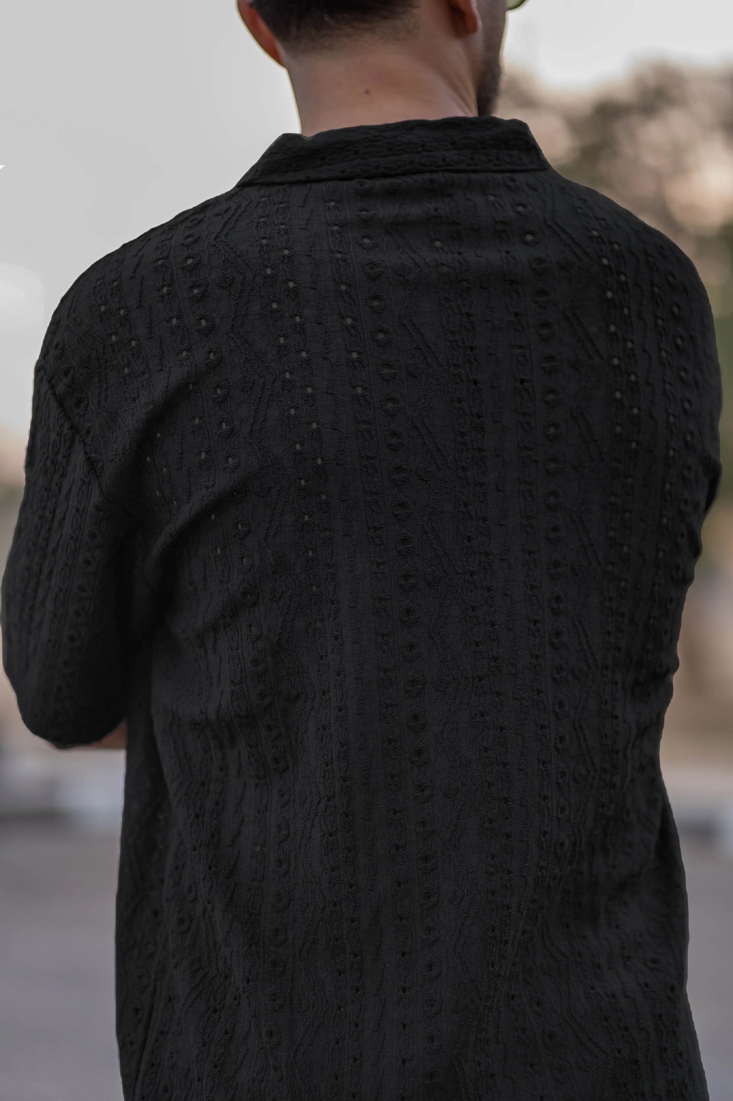 Person wearing a textured black shirt with a blurred background
