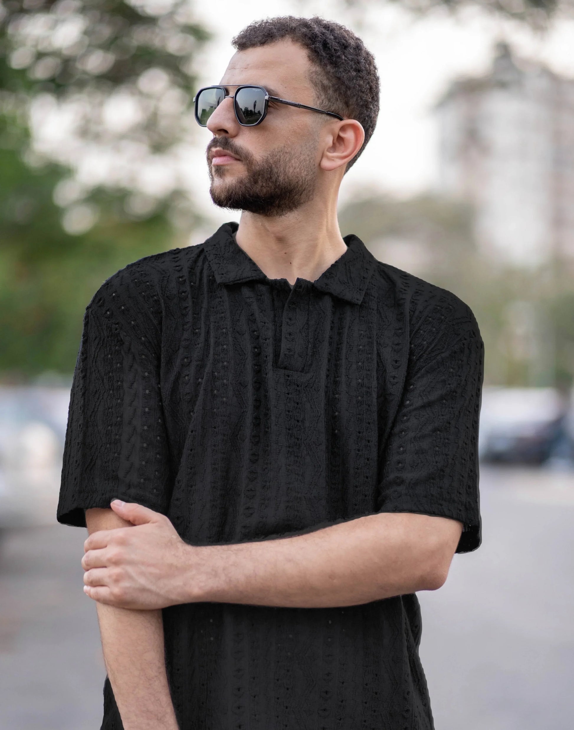 Man wearing a black textured shirt and sunglasses outdoors