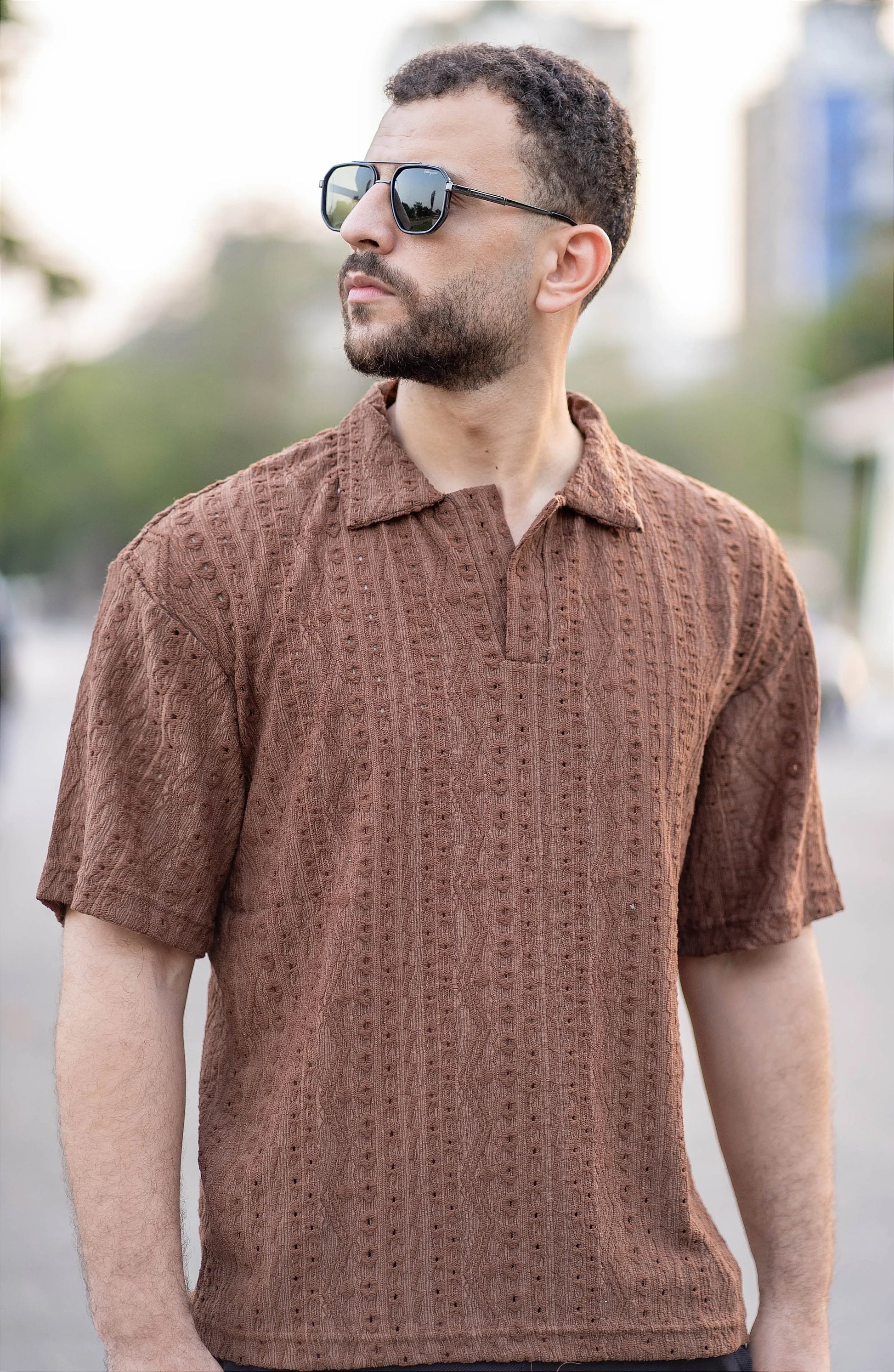 Man wearing a brown patterned shirt outdoors