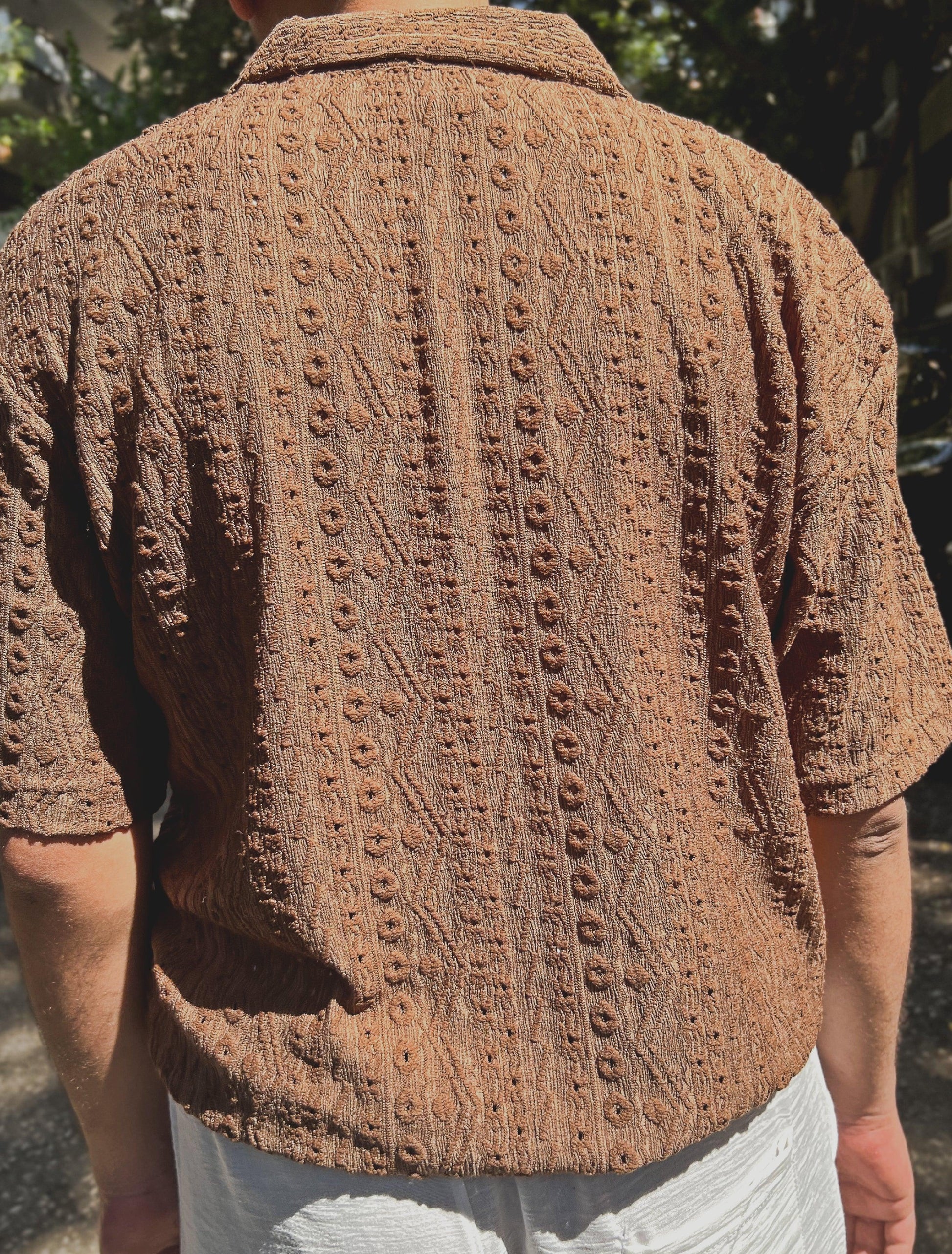 Brown textured short-sleeve shirt worn by a person with a blurred natural background