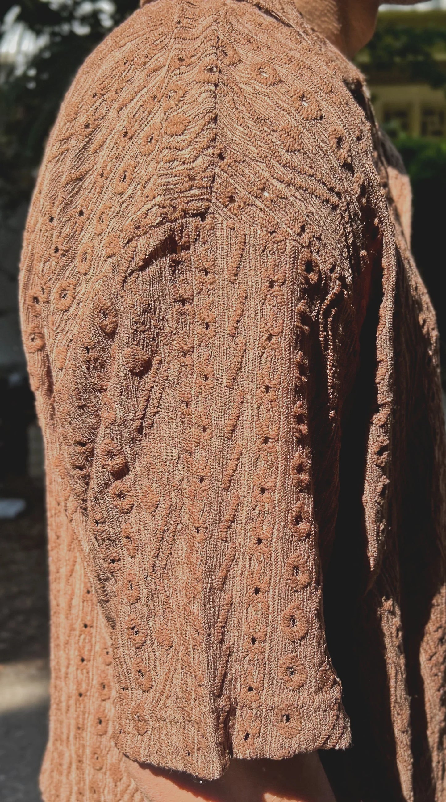 Close-up of a brown knitted garment with intricate patterns.